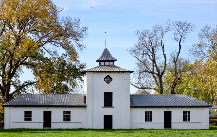 White colonial building with trees.