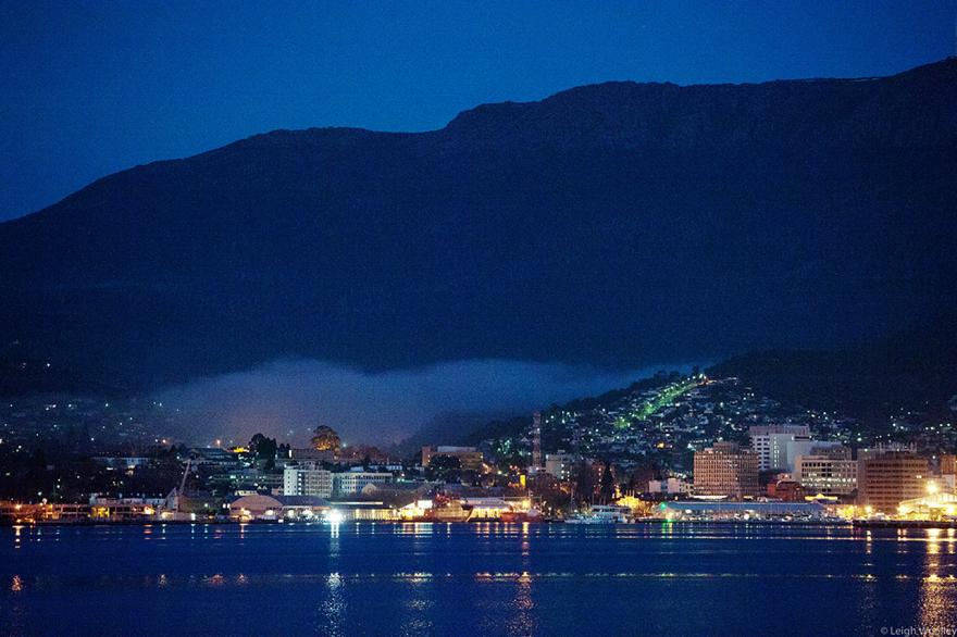 City scene with river and mountain at dusk.