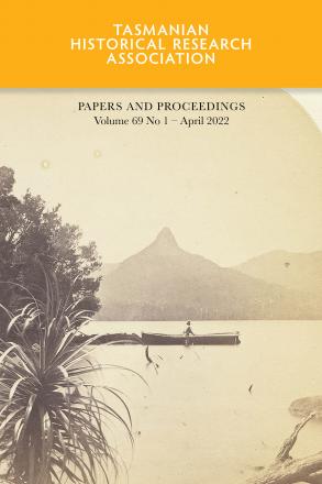 Sepia image of person in boat on lake with mountain in background.
